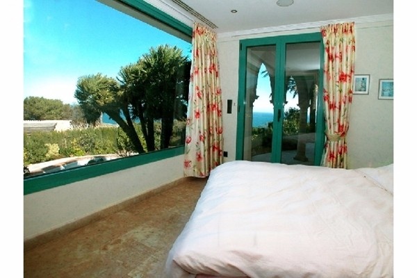 Eines der stilvollen Schlafzimmer mit riesiger Fensterfront und atemberaubendem Ausblick auf das Meer und die malerische Natur